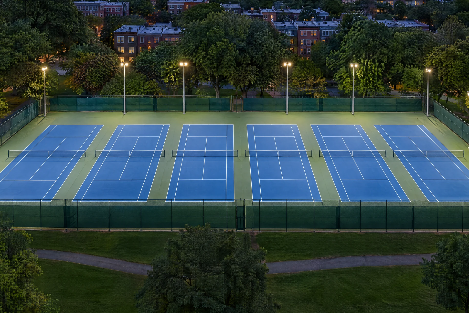 The six courts under floodlights on a weekday evening